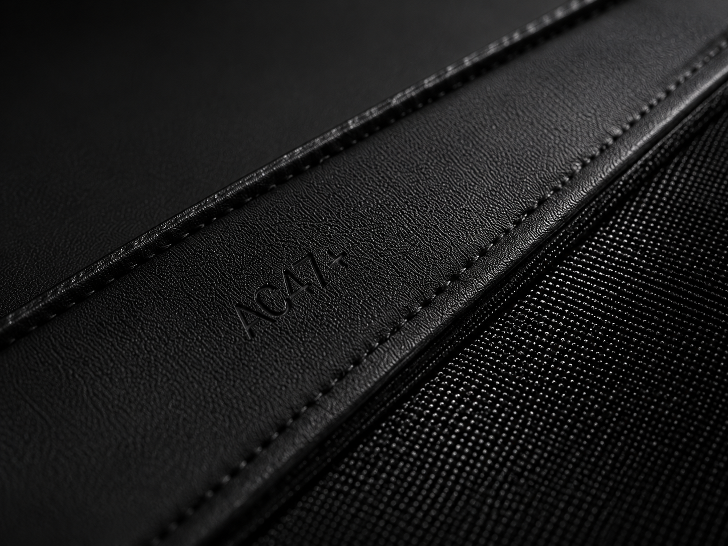 Close view of black leather meeting technical canvas at a stitched seam.